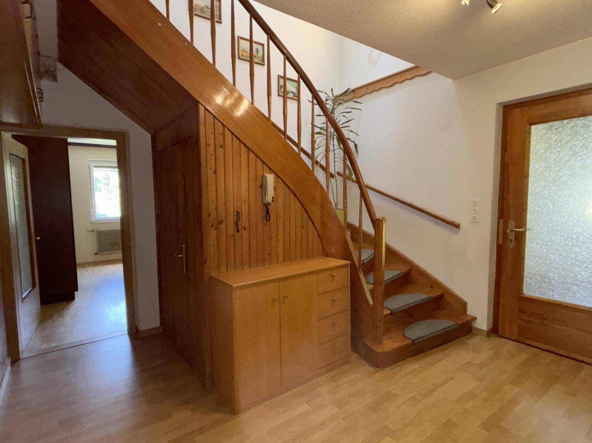 Eingangsbereich mit Holztreppe, Parkettboden und integriertem Stauraum.