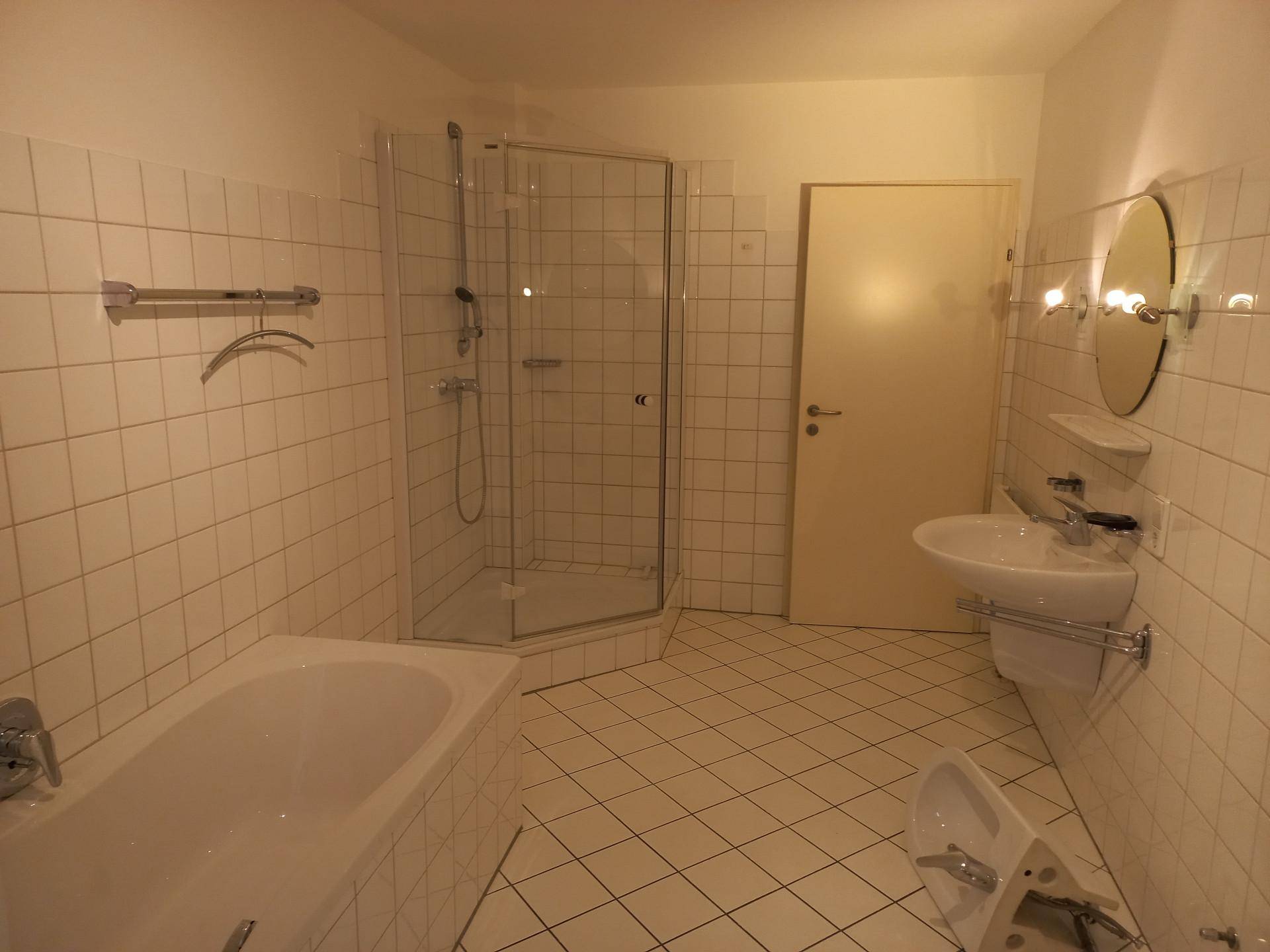 Helles Badezimmer mit Badewanne, Duschkabine, Waschbecken und weißen Fliesen.