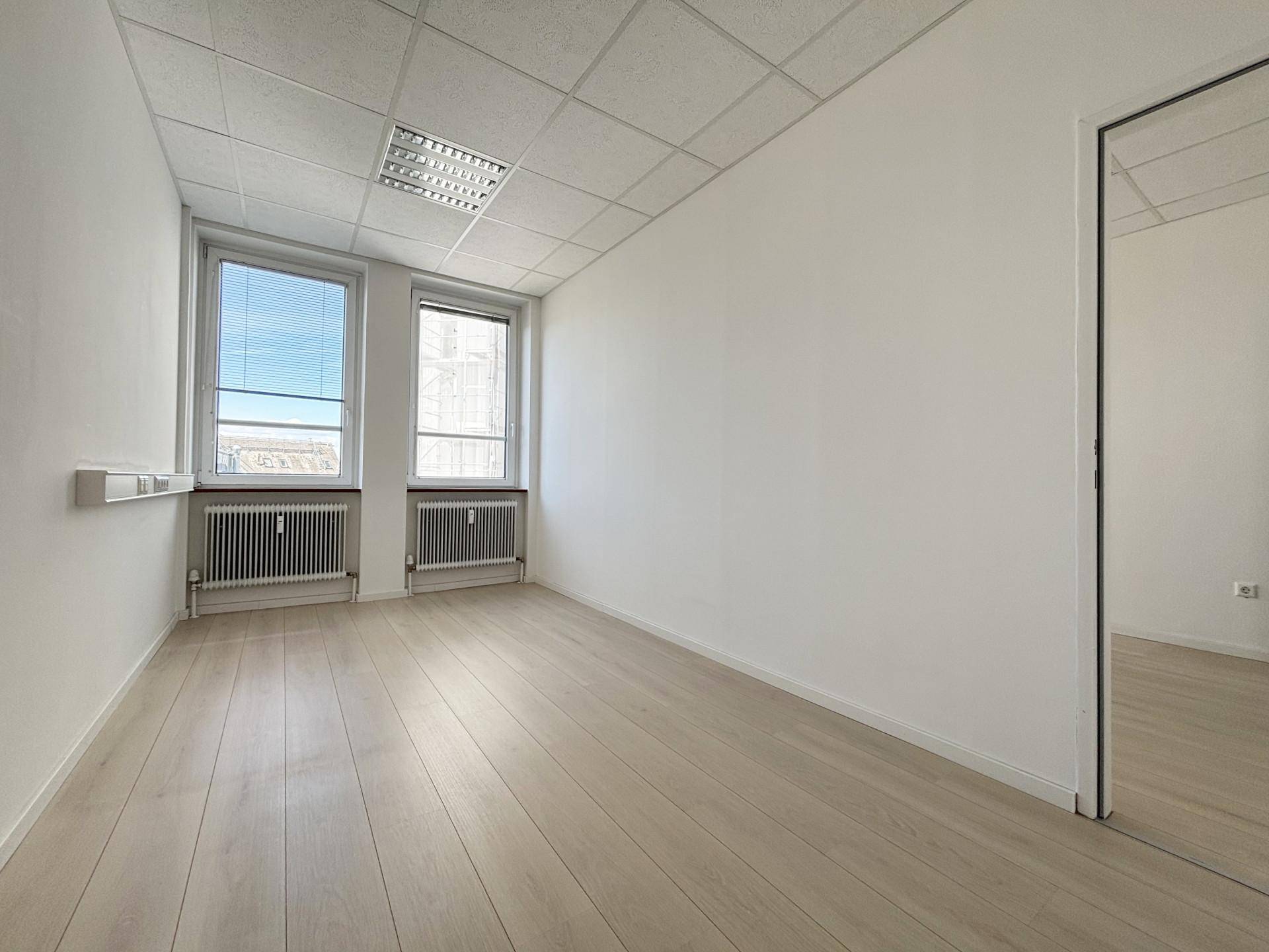Helles Einzelbüro mit zwei Fenstern, Heizkörpern und modernem Laminatboden.