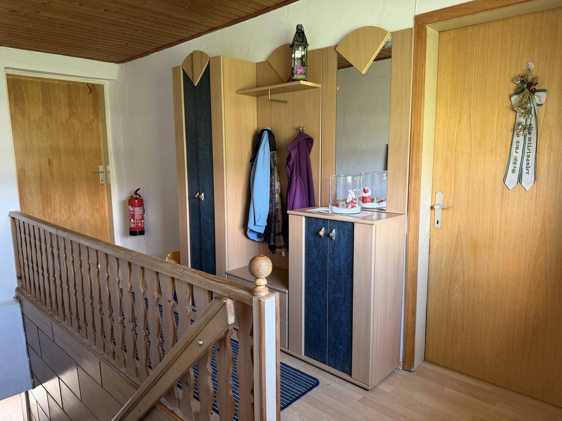 Heller Flur mit Holztreppe, Garderobe und Spiegelschrank, freundlich und funktional gestaltet.
