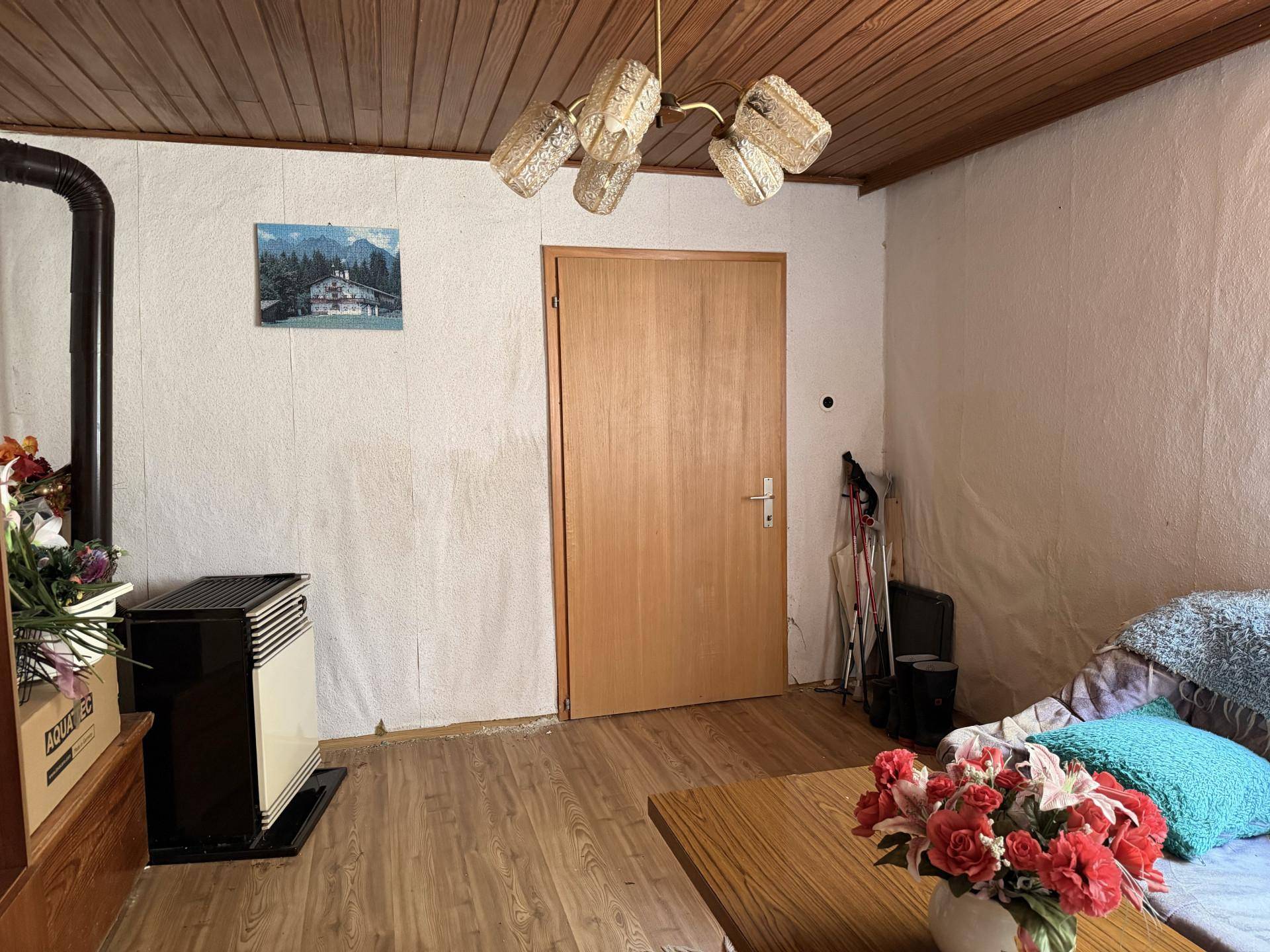 Wohnzimmer mit Holzdecke, Holzboden und einem Ofen, der für Wärme sorgt.