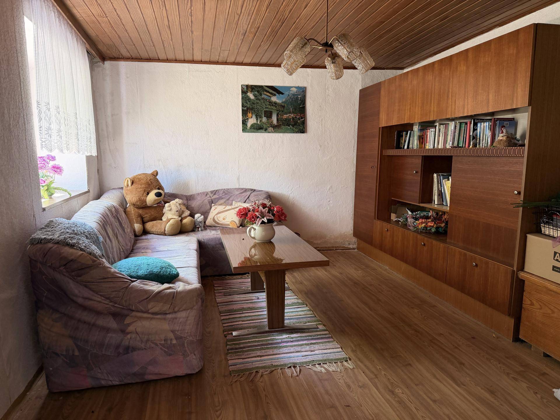 Gemütliches Wohnzimmer mit Ecksofa, Holzdecke und Schrankwand, ideal zum Entspannen.