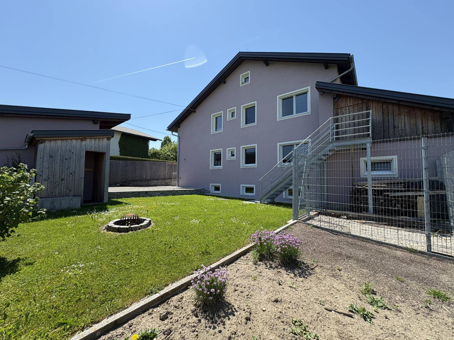 Rückansicht des Hauses mit Garten, Außentreppe und einem kleinen Geräteschuppen.