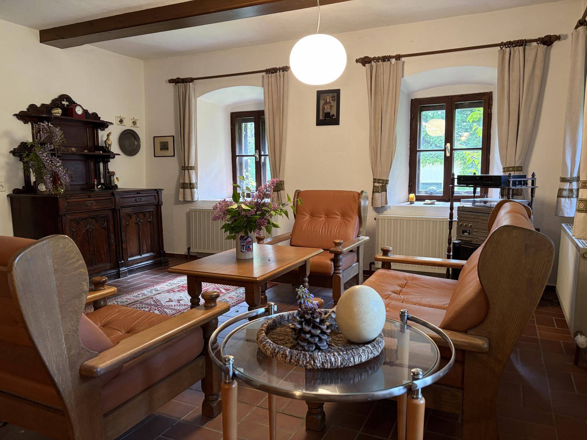 Traditionelles Wohnzimmer mit Terrakotta-Fliesen, Holzbalken und bequemen Ledersesseln, hell und einladend.
