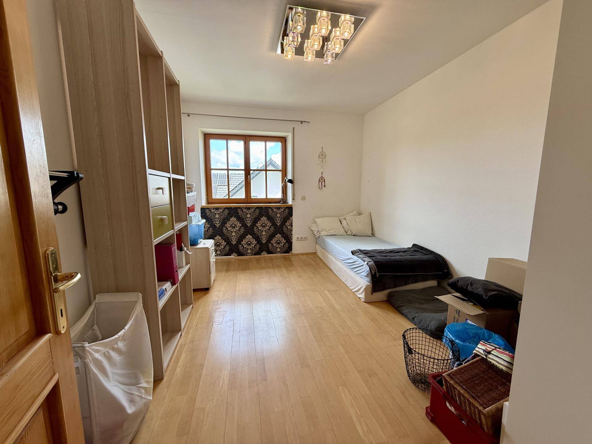 Helles Schlafzimmer mit Holzboden, Schrankwand und dekorativer Tapete an der Fensterwand.