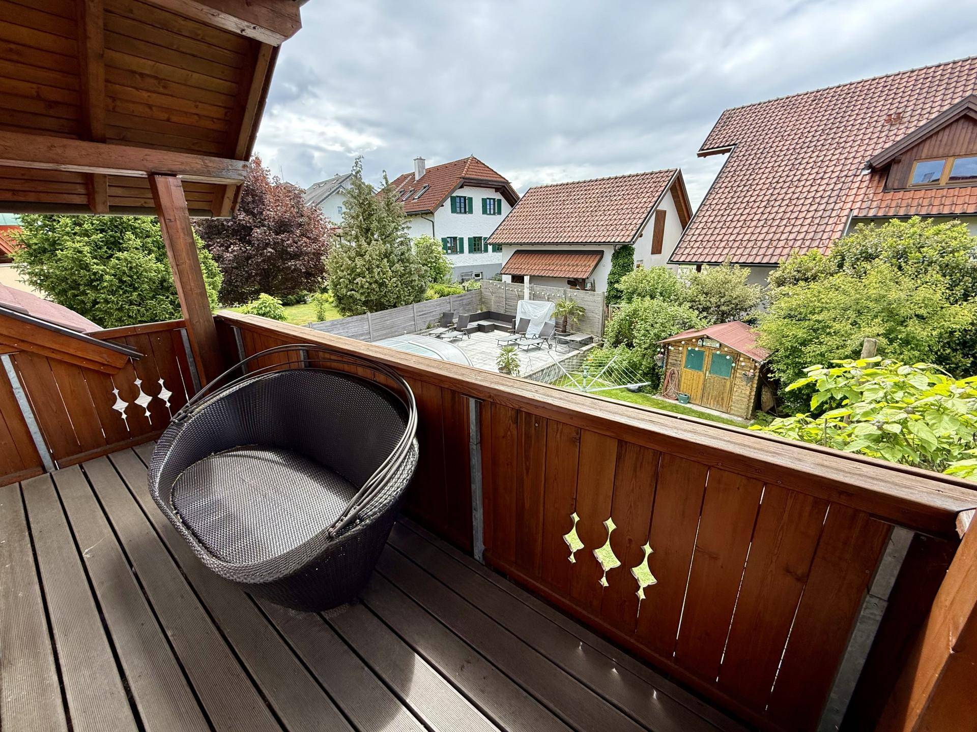 Gemütlicher Balkon mit Holzboden, Sitzgelegenheit und Blick auf den Garten und die Nachbarschaft.