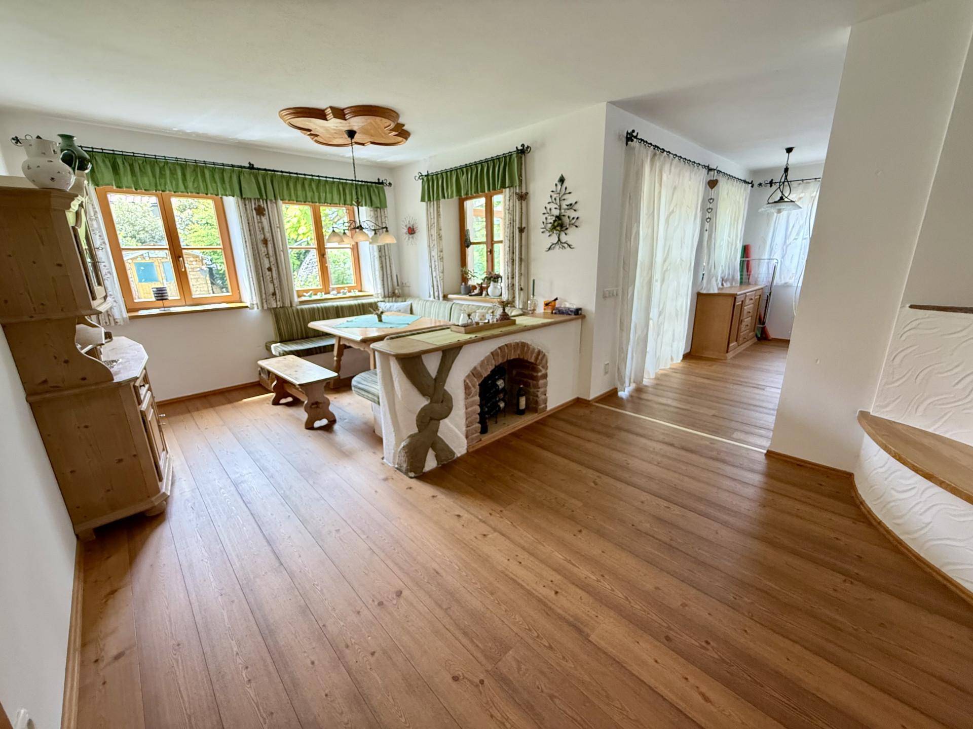 Traditioneller Essbereich mit Holzboden, Eckbank und rustikalem Kamin im Hintergrund.