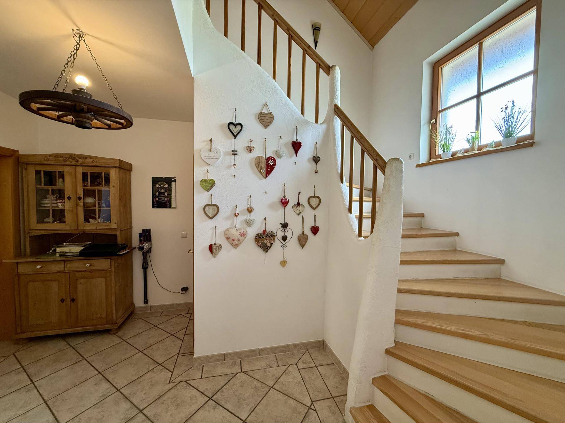 Treppenhaus mit Holzstufen, Fliesenboden und dekorativen Herzen an der Wand.