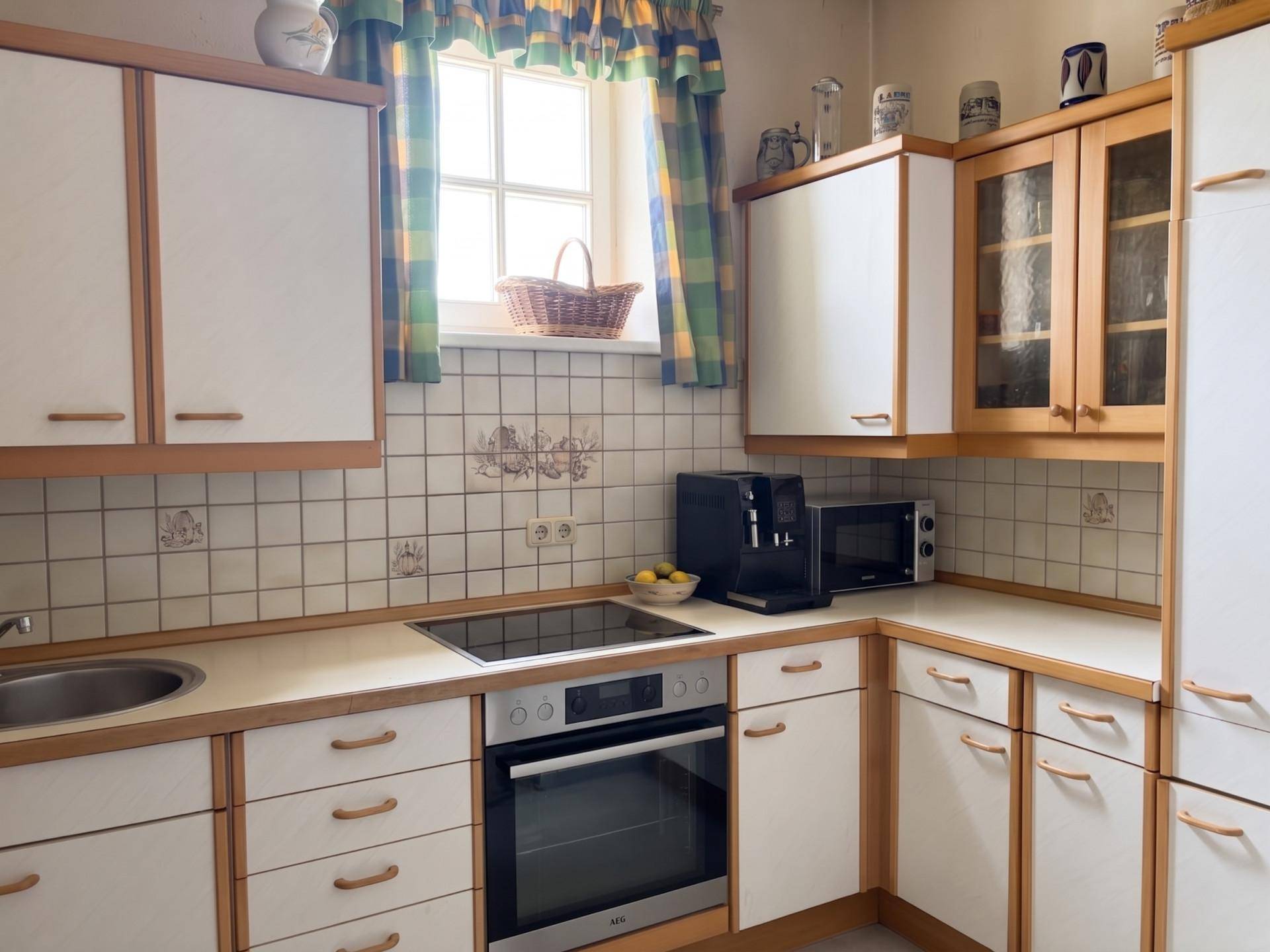 Gemütliche Küche mit weißen und holzfarbenen Schränken, einem Fenster und integrierten Geräten.