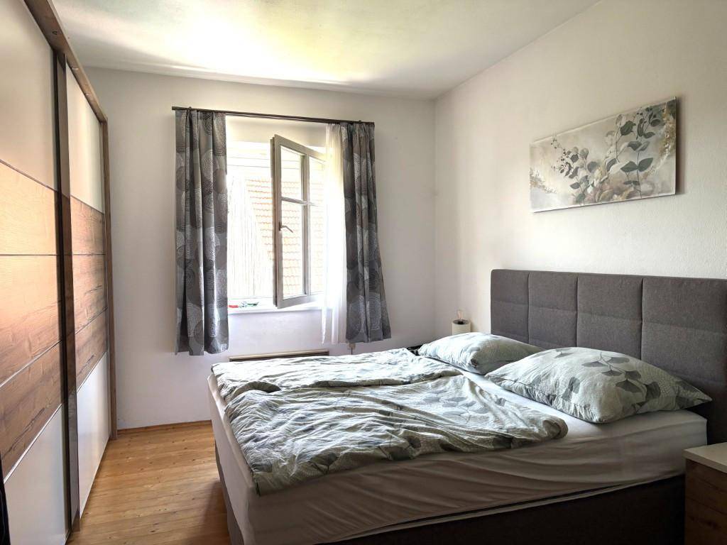Helles Schlafzimmer mit Doppelbett, großem Kleiderschrank und einem geöffneten Fenster.