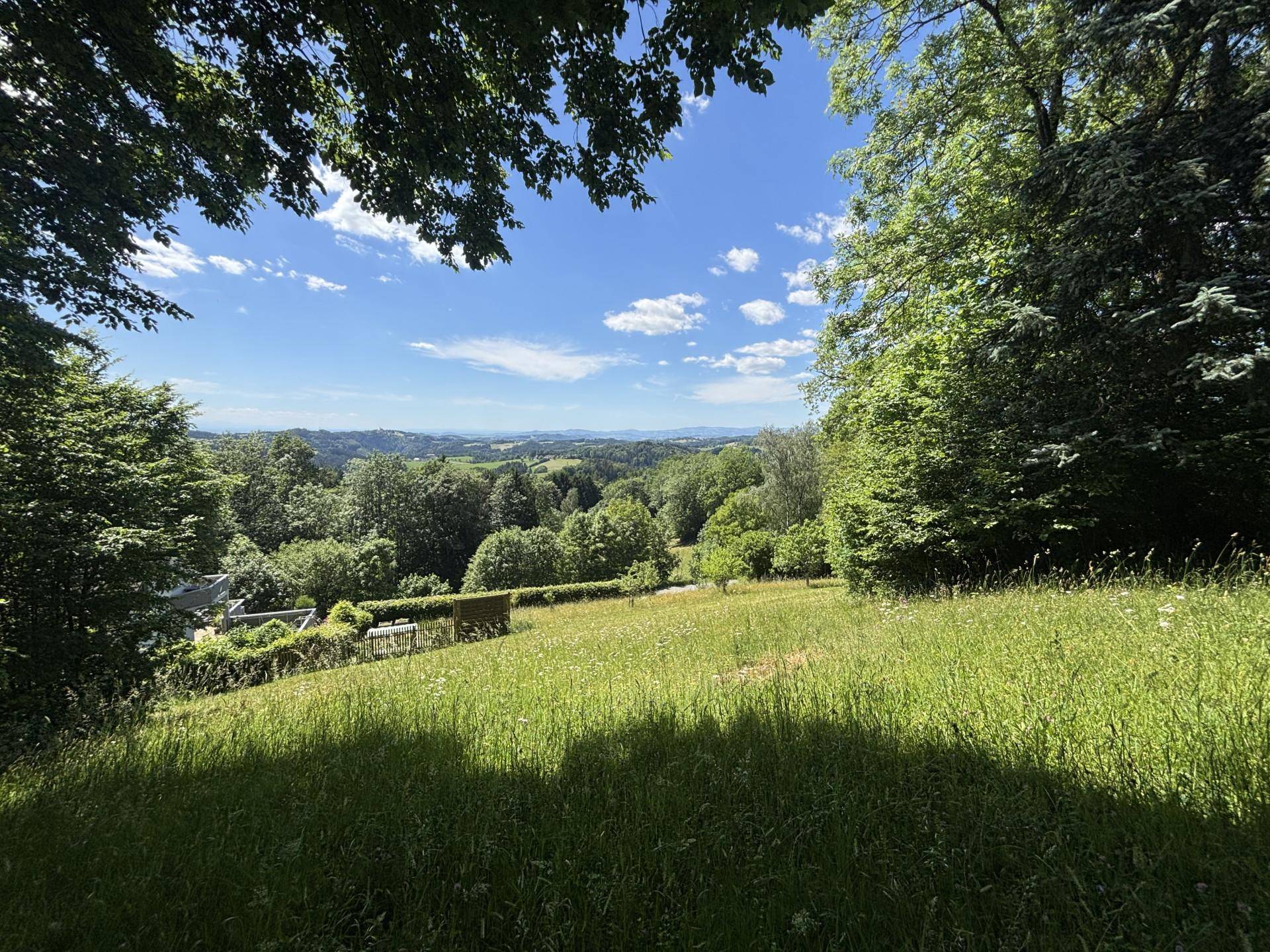 Idyllischer Ausblick auf die weite grüne Landschaft mit Wäldern und Feldern an einem sonnigen Tag.