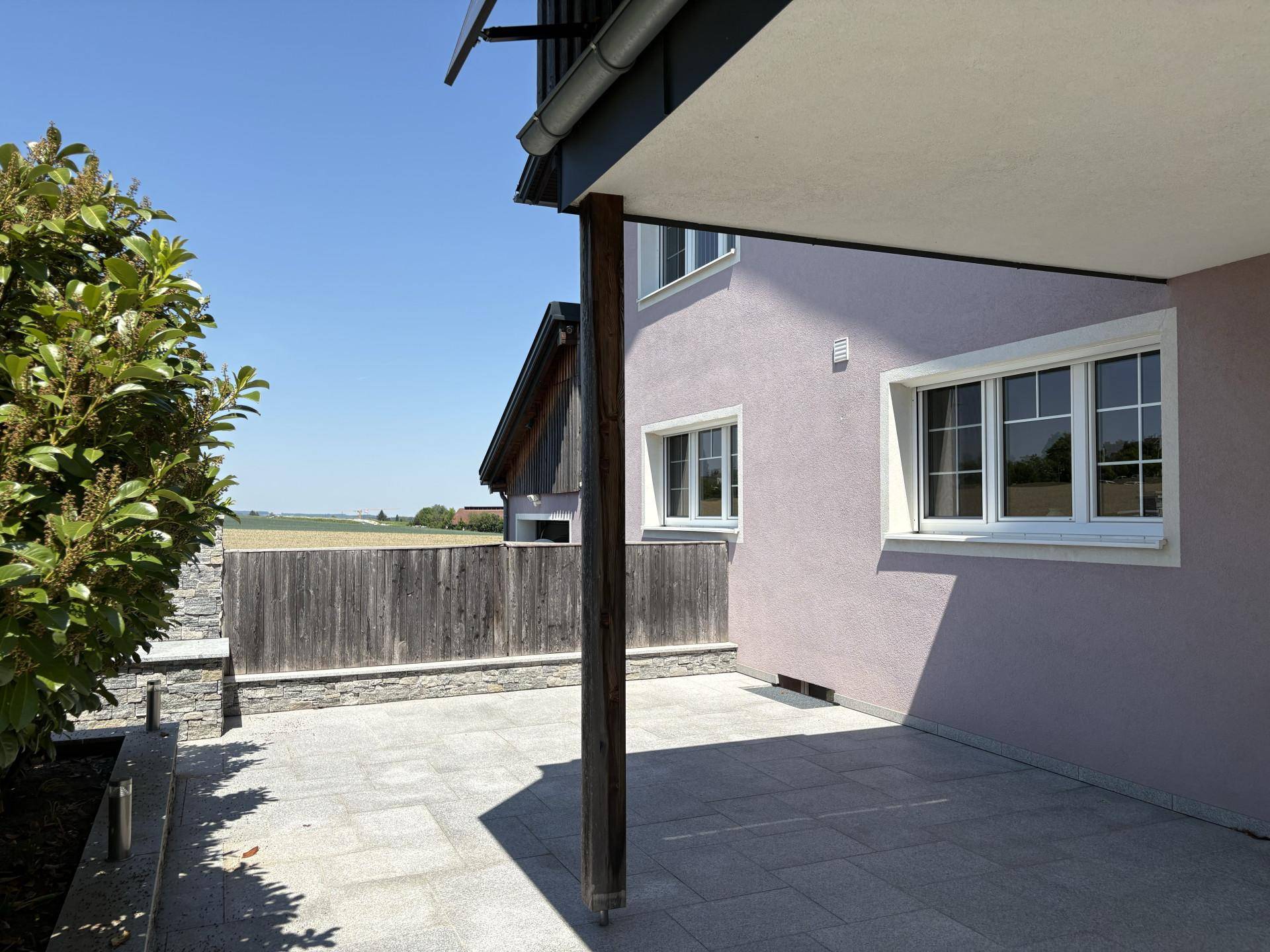 Überdachte Terrasse mit Steinboden und Blick auf die weite Landschaft.