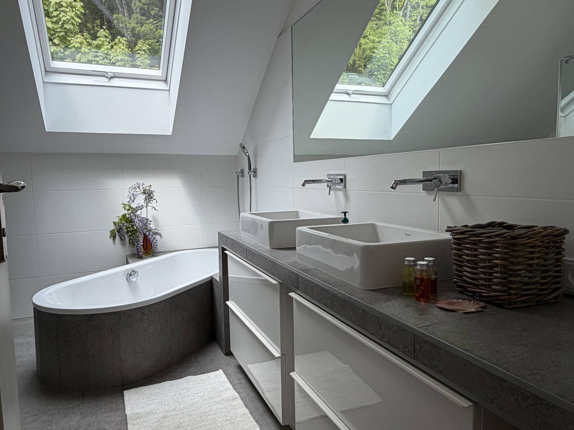 Modernes Badezimmer im Dachgeschoss mit freistehender Badewanne, Doppelwaschbecken und Dachfenstern.