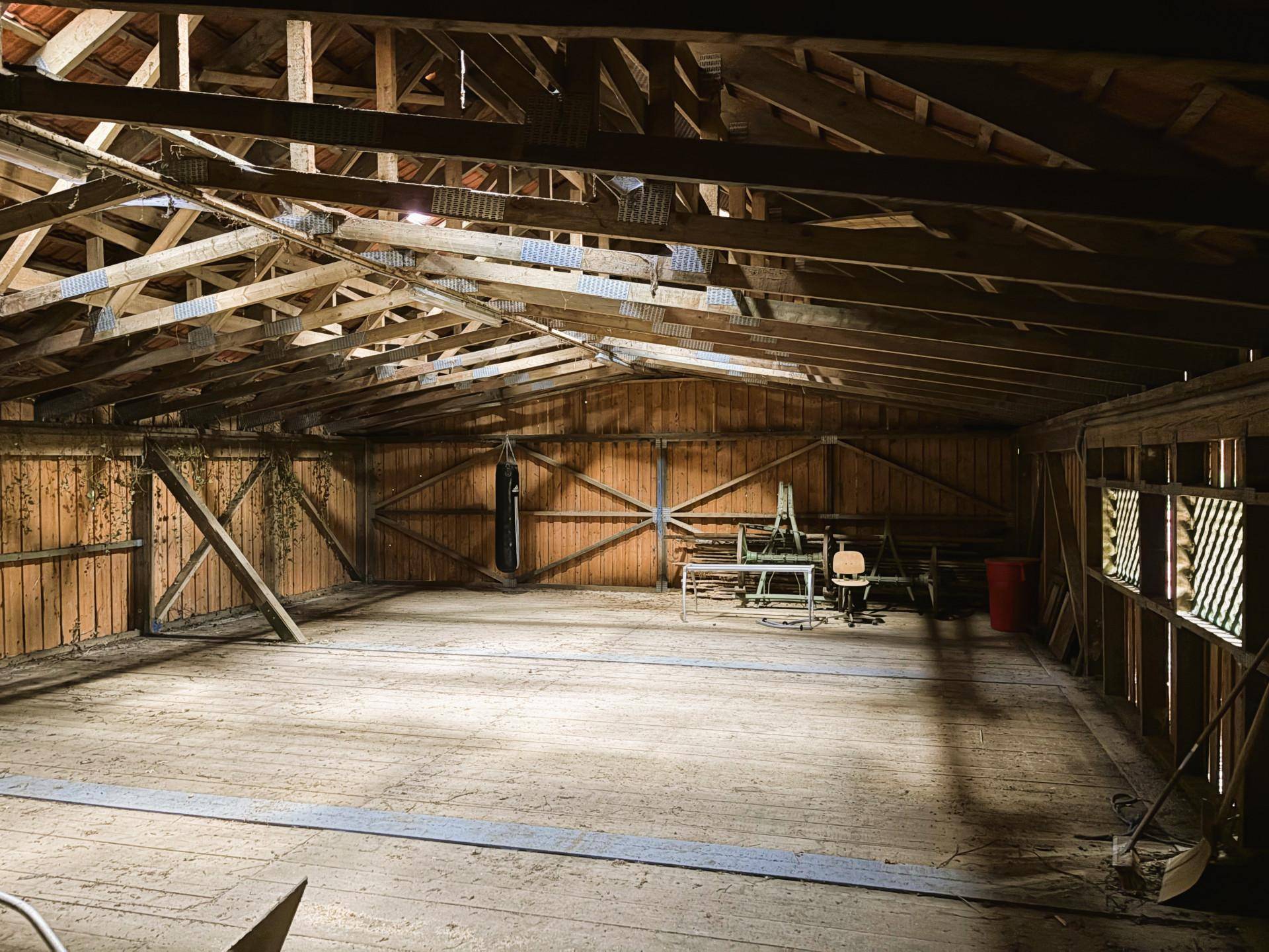 Geräumiger Dachboden oder Scheunenraum mit sichtbaren Holzdachbalken und Holzdielenboden, bereit zur Nutzung.