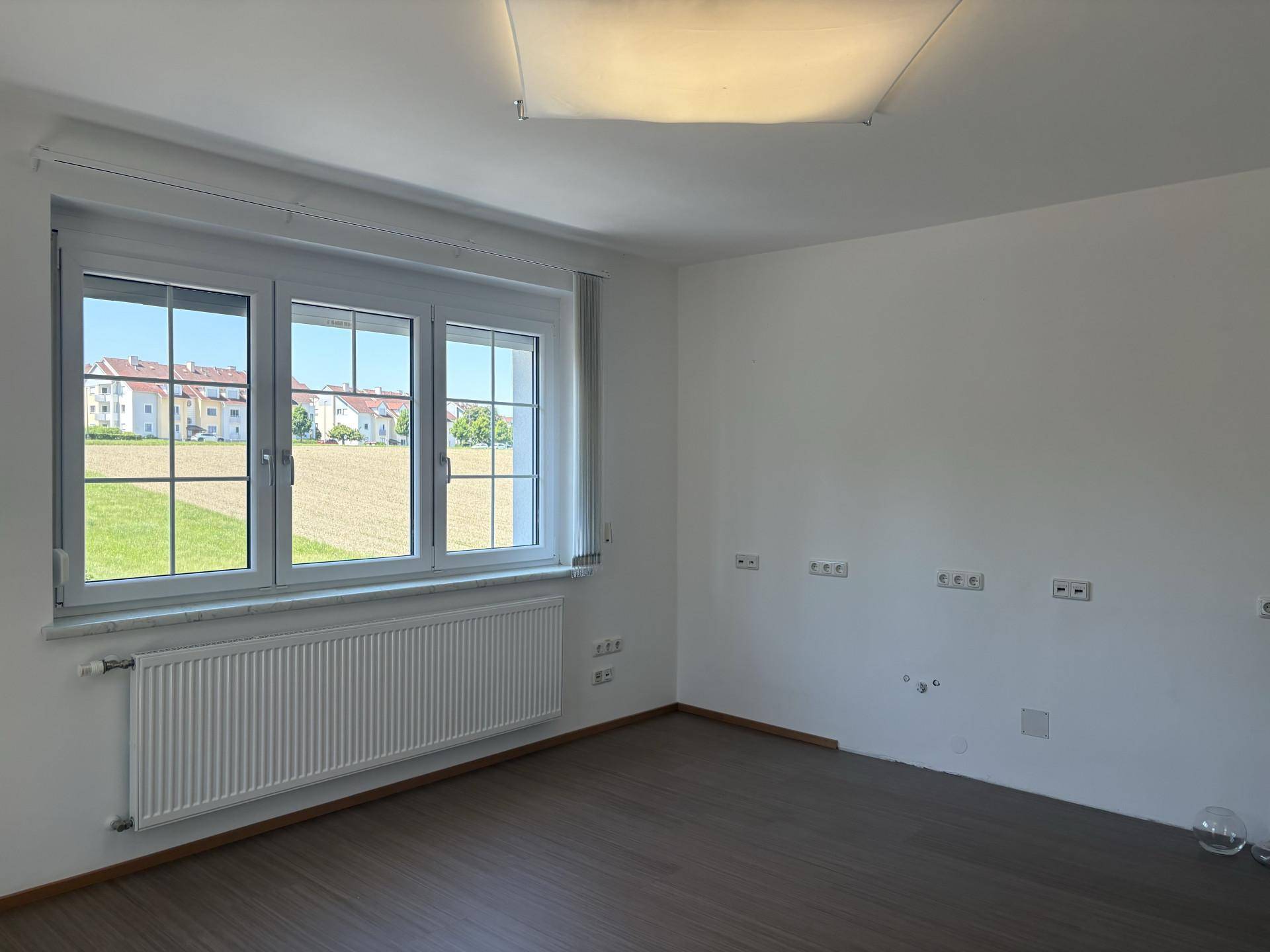 Leerer Raum mit Laminatboden und weitem Blick über die umliegenden Felder.