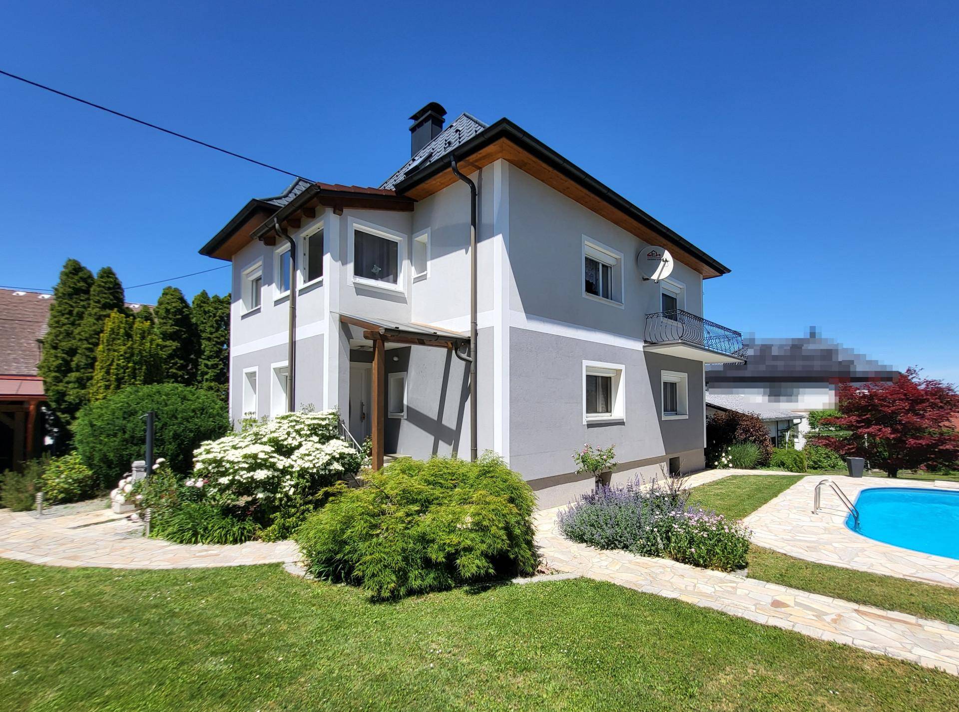 Freistehendes Haus mit Pool und gepflegtem Garten an einem sonnigen Tag.