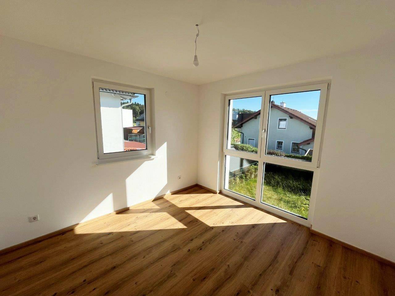 Helles Zimmer mit zwei Fenstern, Laminatboden und sonnigem Ambiente.