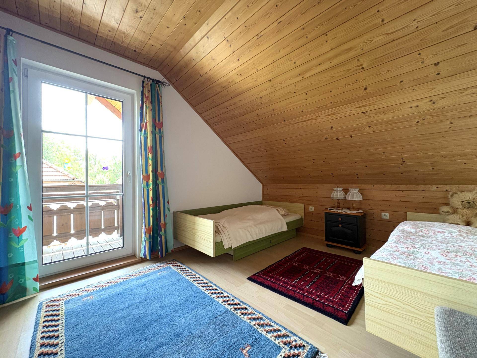 Gemütliches Schlafzimmer im Dachgeschoss mit Holzverkleidung und Balkonzugang.