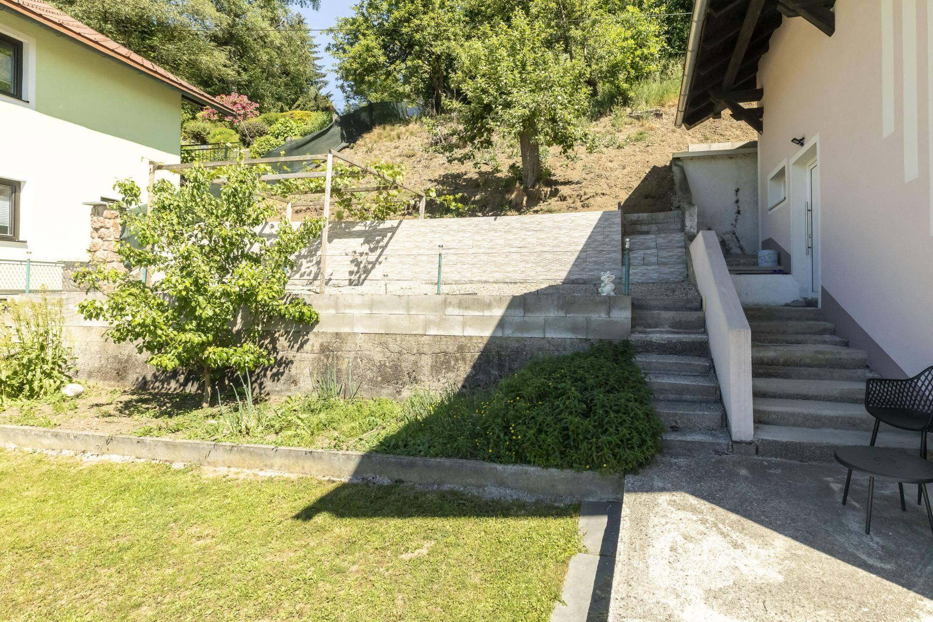 Gartenbereich mit Treppen, Grünflächen und natürlicher Hanglage hinter dem Haus.
