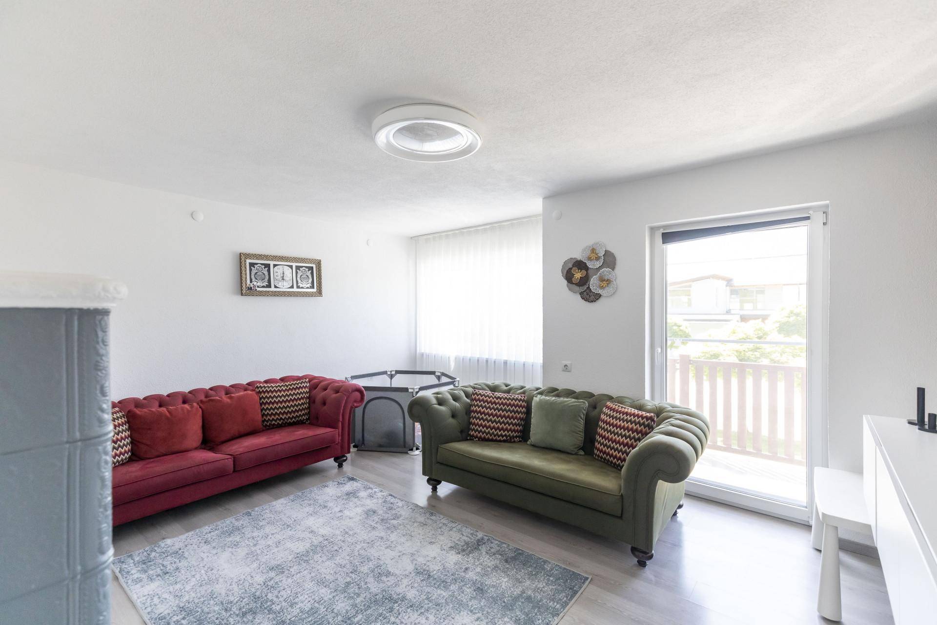 Helles Wohnzimmer mit zwei Sofas, Teppich und Zugang zu einem kleinen Balkon.