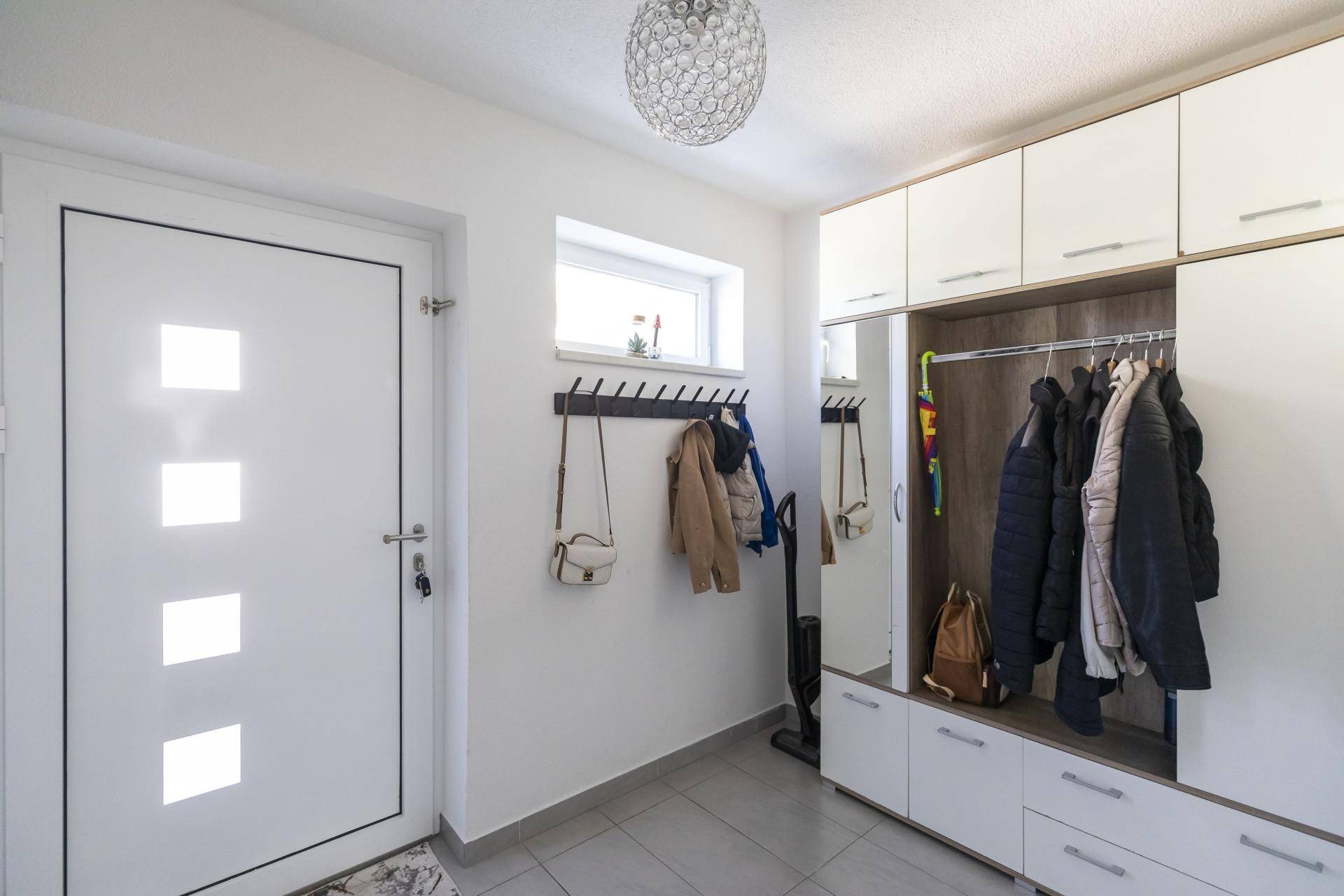 Heller Eingangsbereich mit Garderobe, Spiegel und praktischem Fliesenboden.