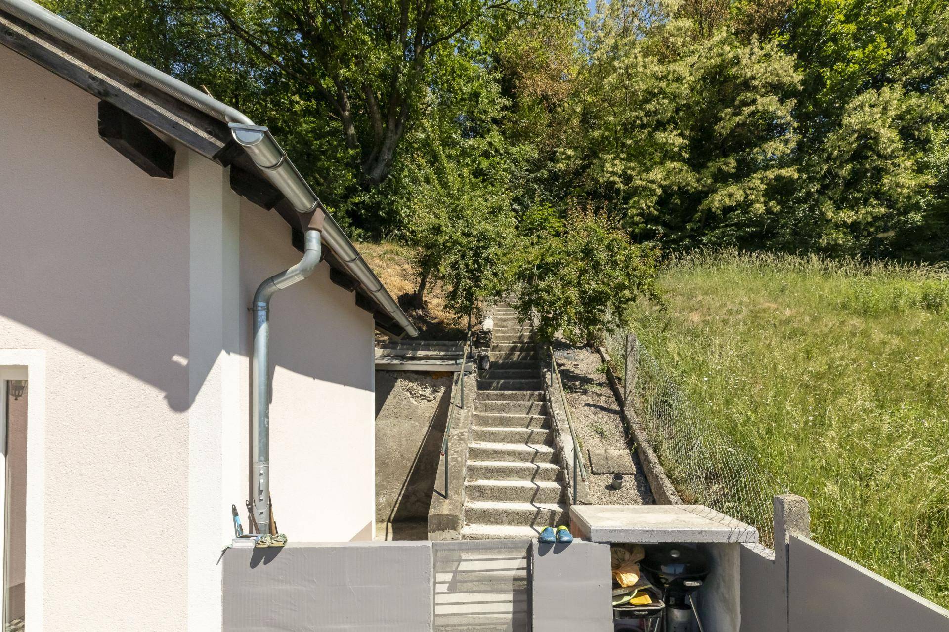 Gartenbereich mit Treppen zum oberen Hang und einem kleinen Grillplatz.