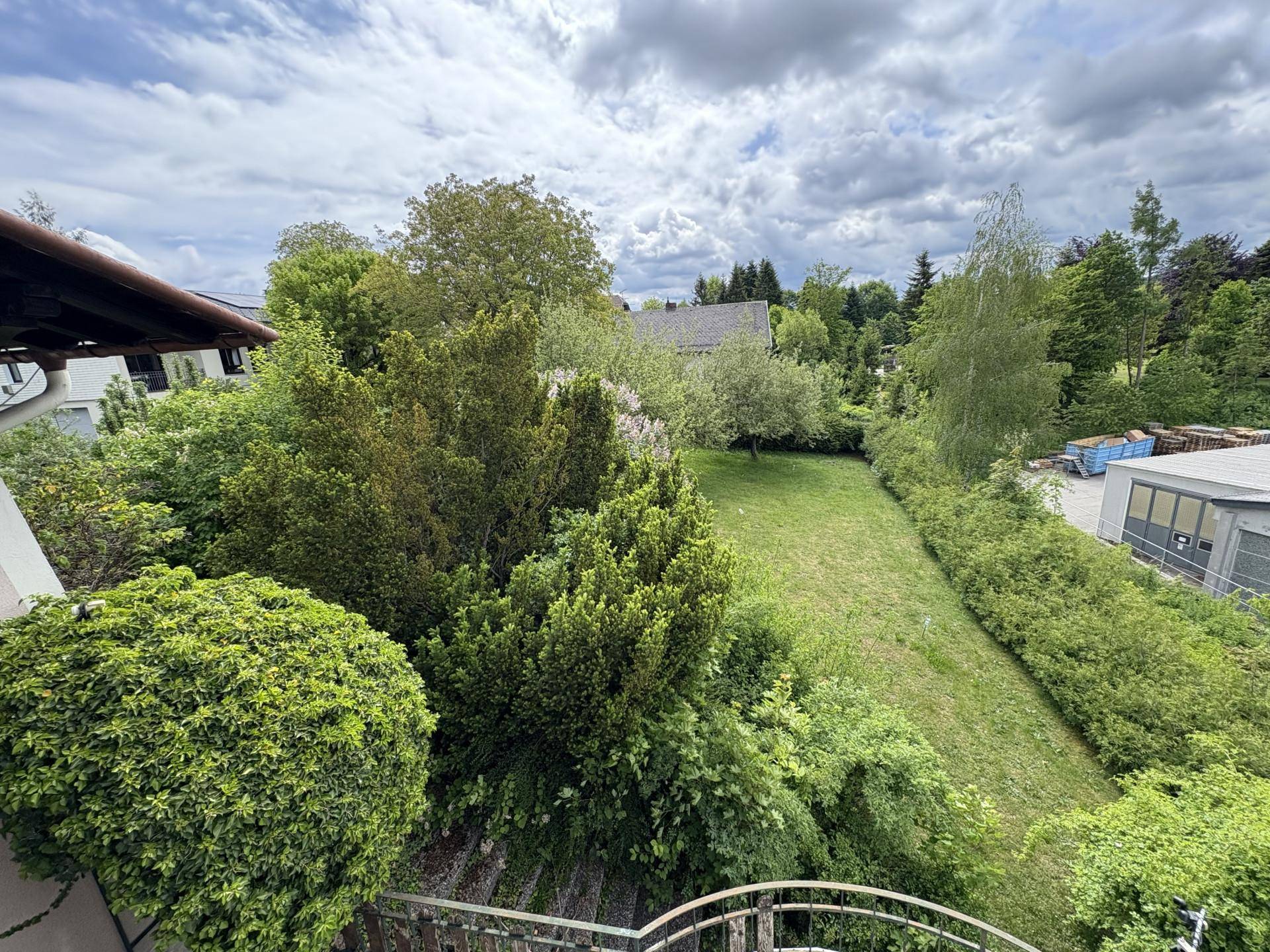 Großer, gepflegter Garten mit Rasenfläche, Hecken und Bäumen, von oben betrachtet.
