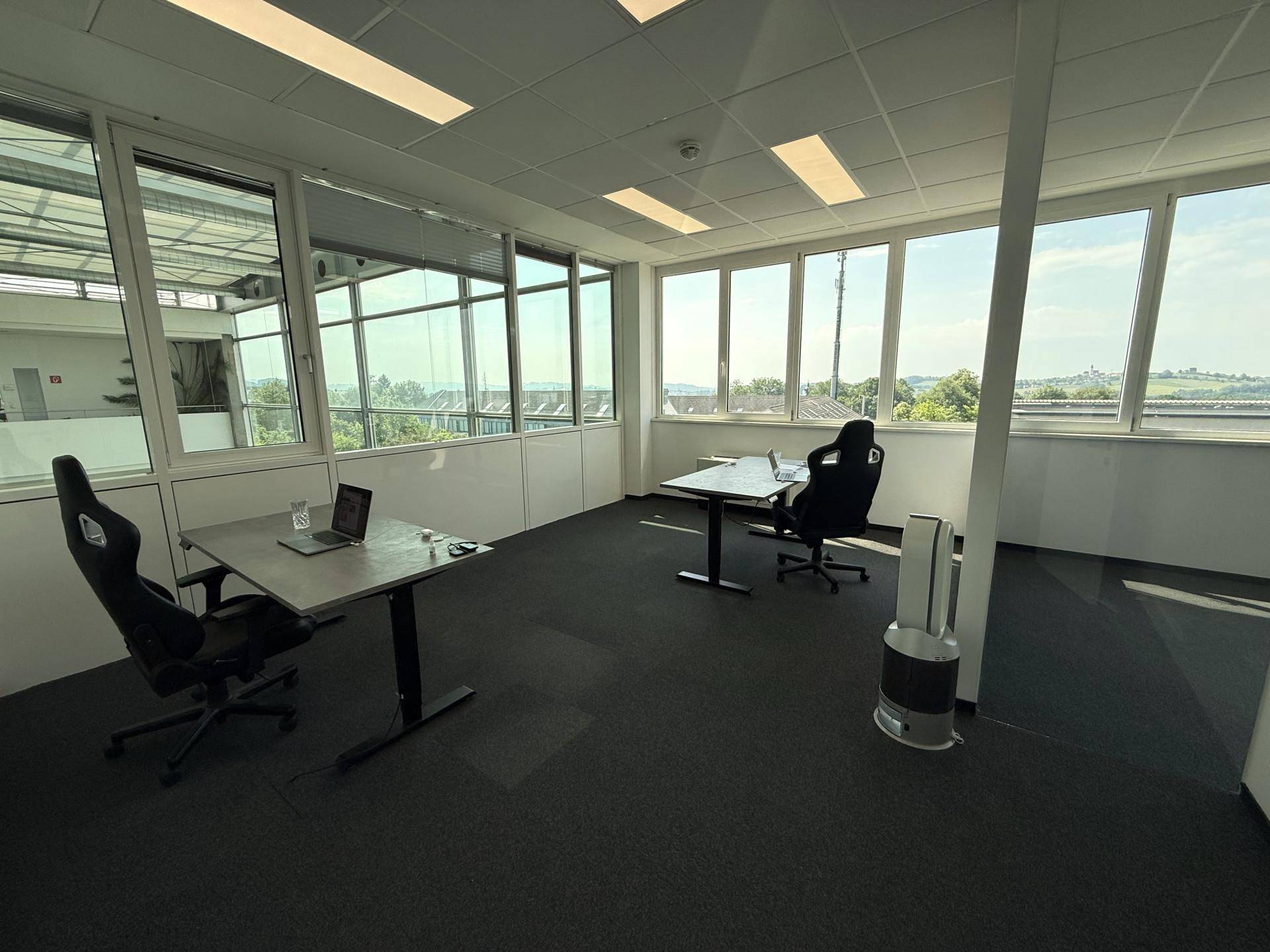 Helles Büro mit zwei Arbeitsplätzen, ergonomischen Stühlen und weitem Ausblick durch große Fenster.