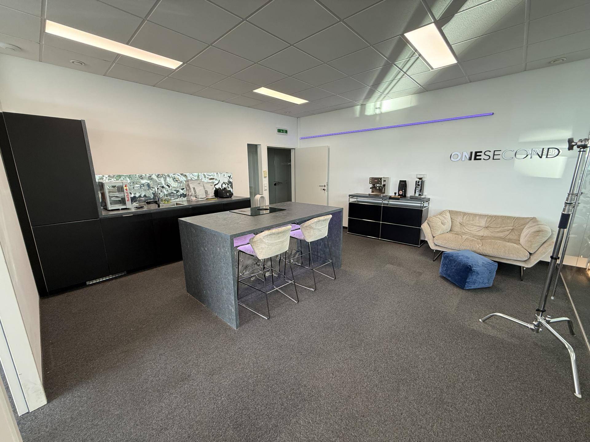 Geräumiges Büro mit Küchenzeile, gemütlichem Sofa und moderner Einrichtung für kreative Arbeitsbereiche.