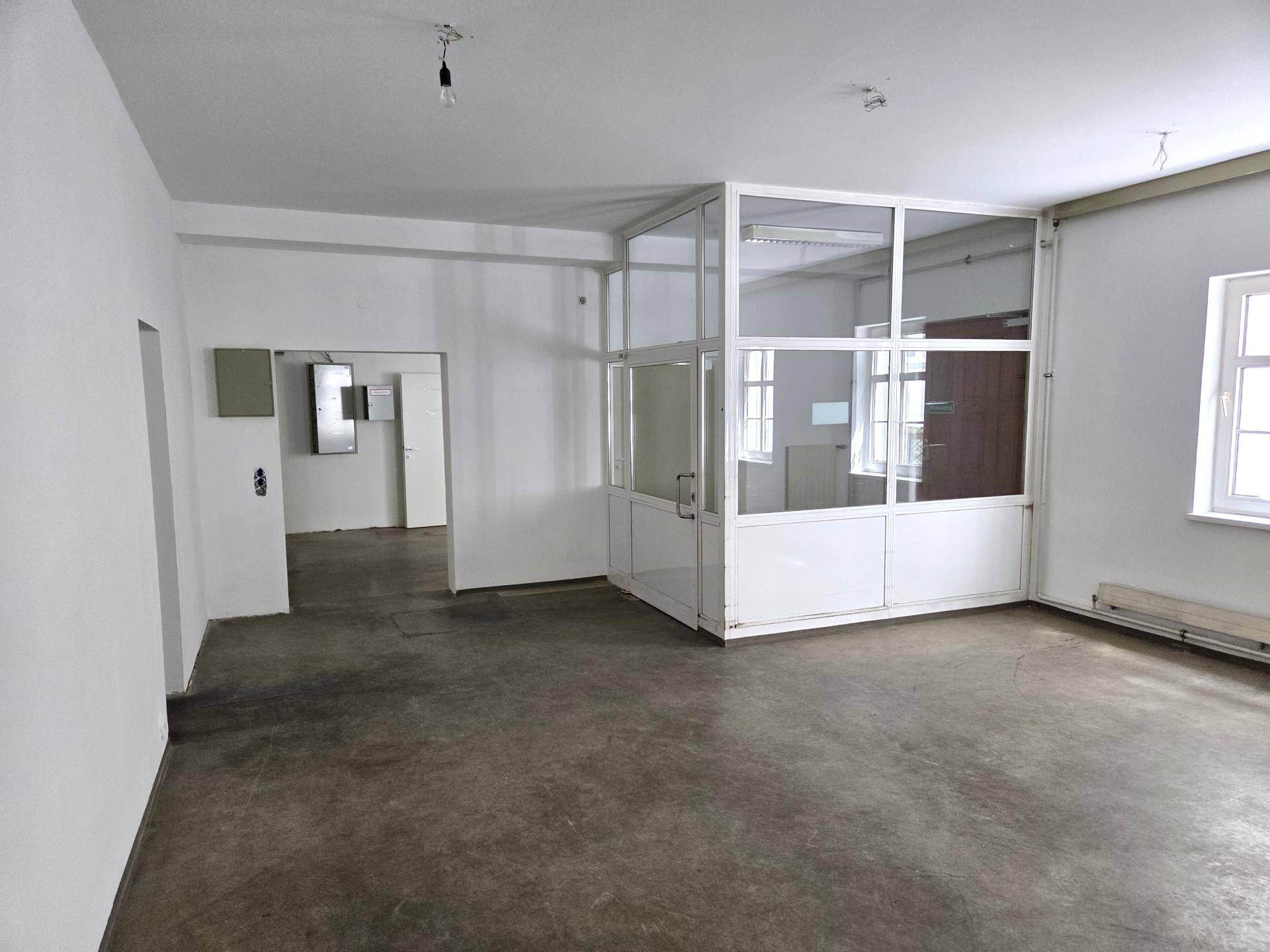 Leerer Raum mit Betonboden und einer modernen Glasabtrennung, ideal für ein Büro.