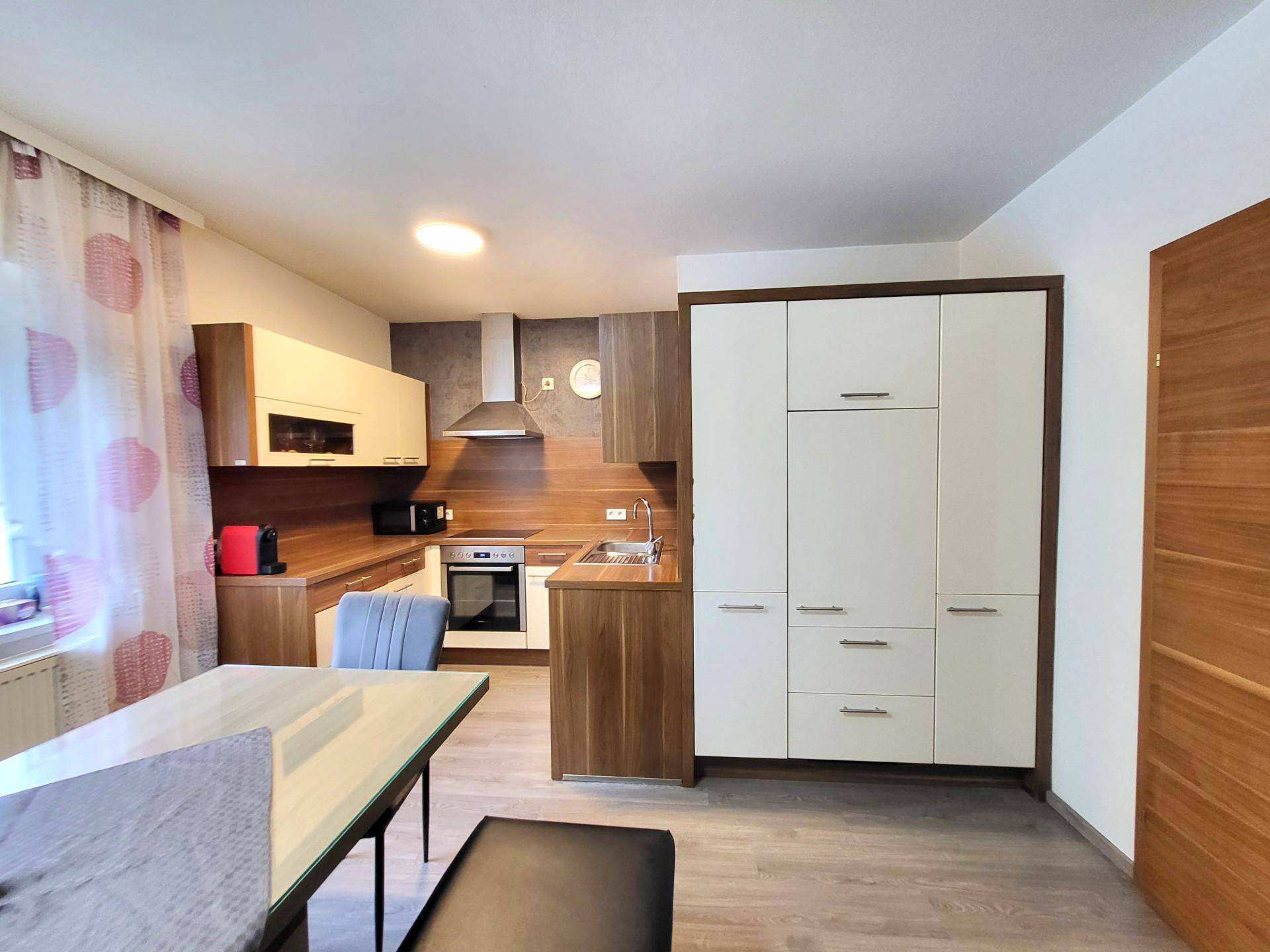 Moderne Einbauküche mit Holzfronten und hellen Oberschränken, ausgestattet mit modernen Geräten.