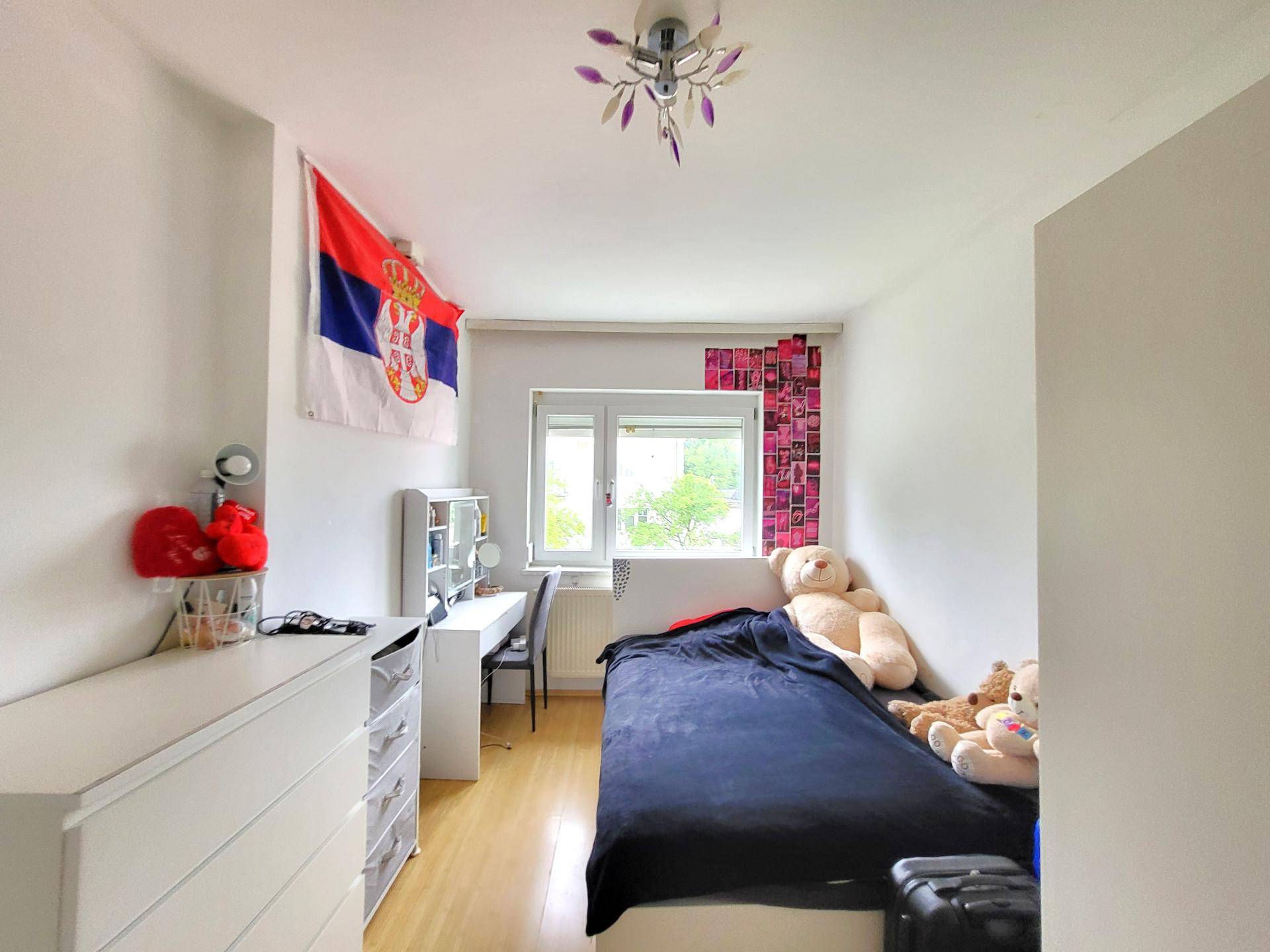 Helles Kinderzimmer mit Einzelbett, Schreibtisch und Fenster.