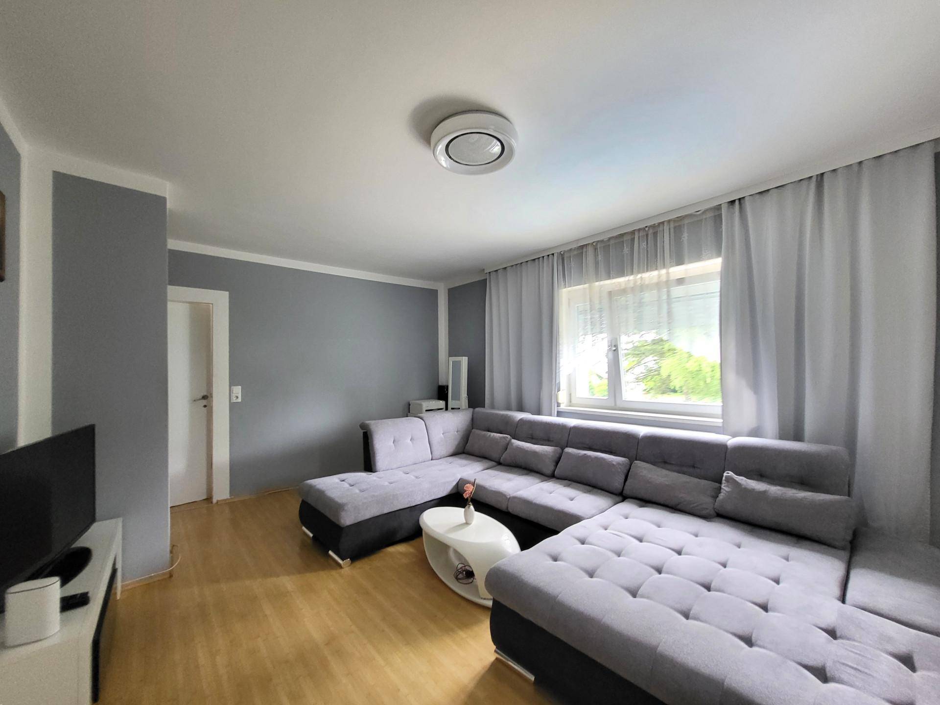 Modernes Wohnzimmer mit grau gestrichenen Wänden und großem Ecksofa.
