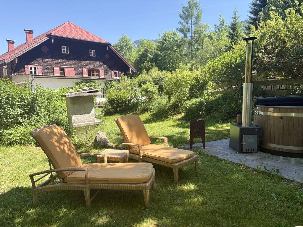 Sonniger Gartenbereich mit Liegestühlen, Whirlpool und Blick auf die Berge.
