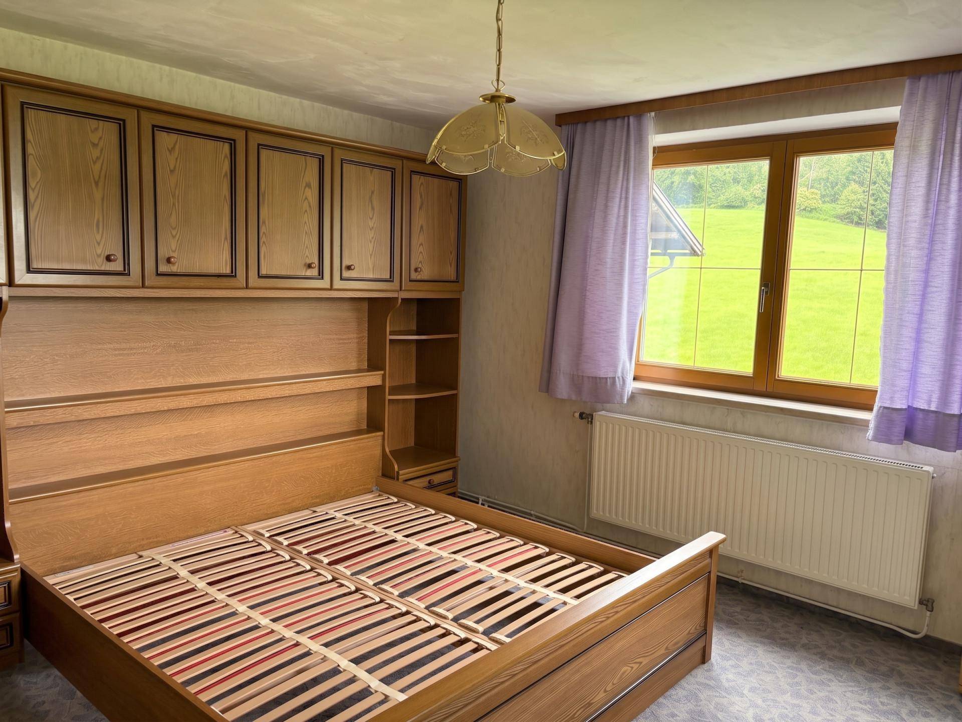 Schlafzimmer mit Doppelbett, Einbauschränken und einem Fenster mit Blick auf die Landschaft.