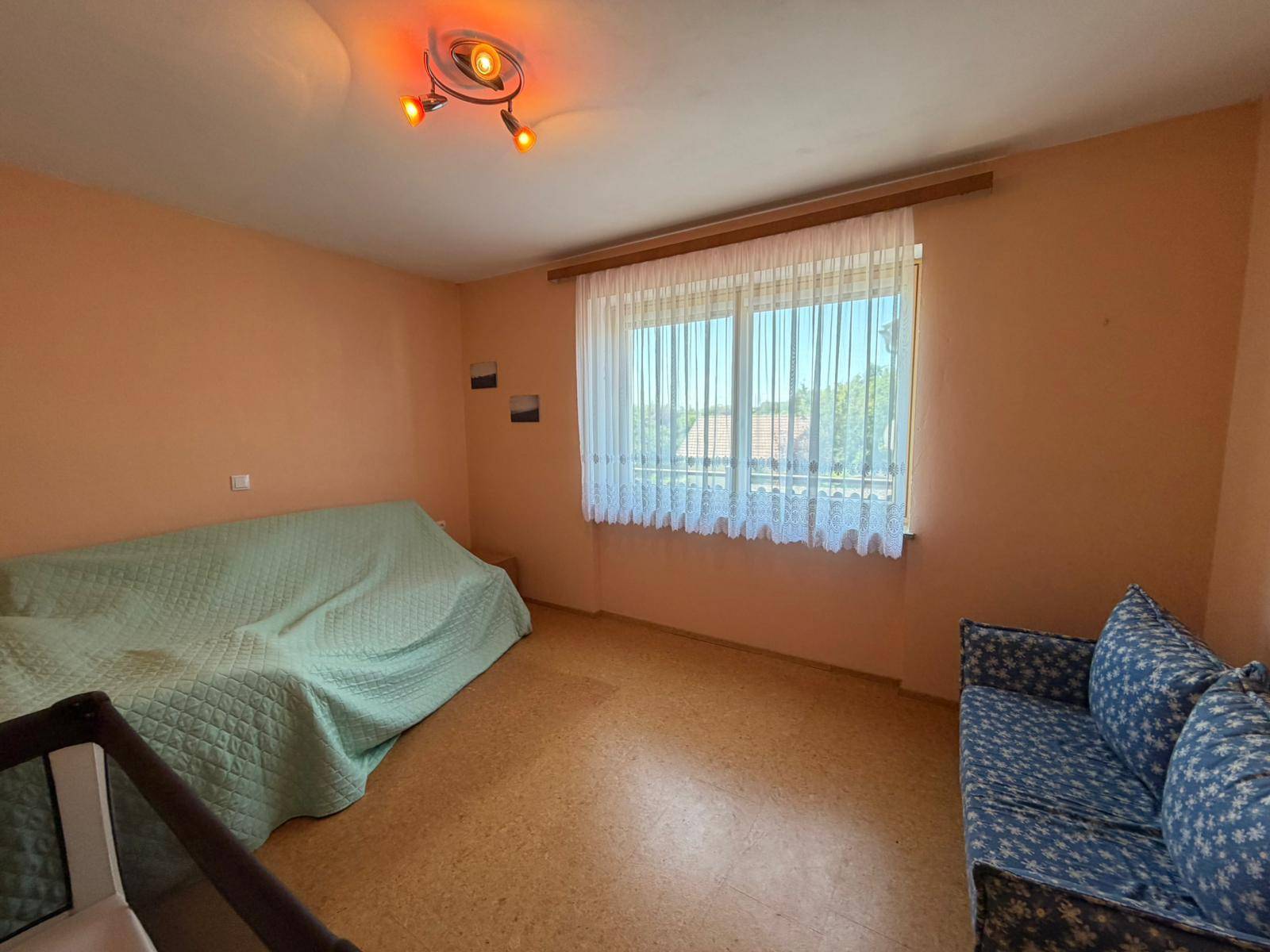Gemütliches Zimmer mit Schlafsofa und Fenster, ideal als Gäste- oder Kinderzimmer nutzbar.