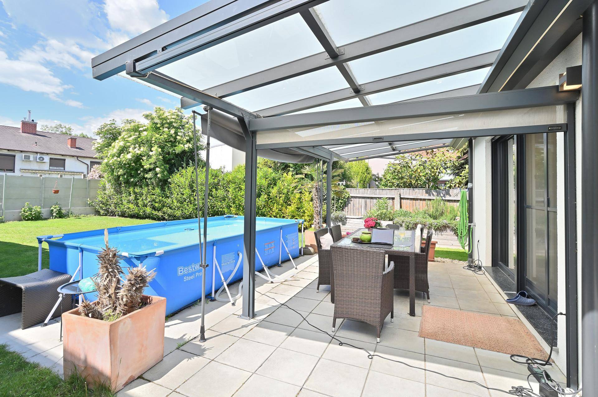 Geräumige überdachte Terrasse mit Essbereich und direktem Zugang zum Garten mit Pool.