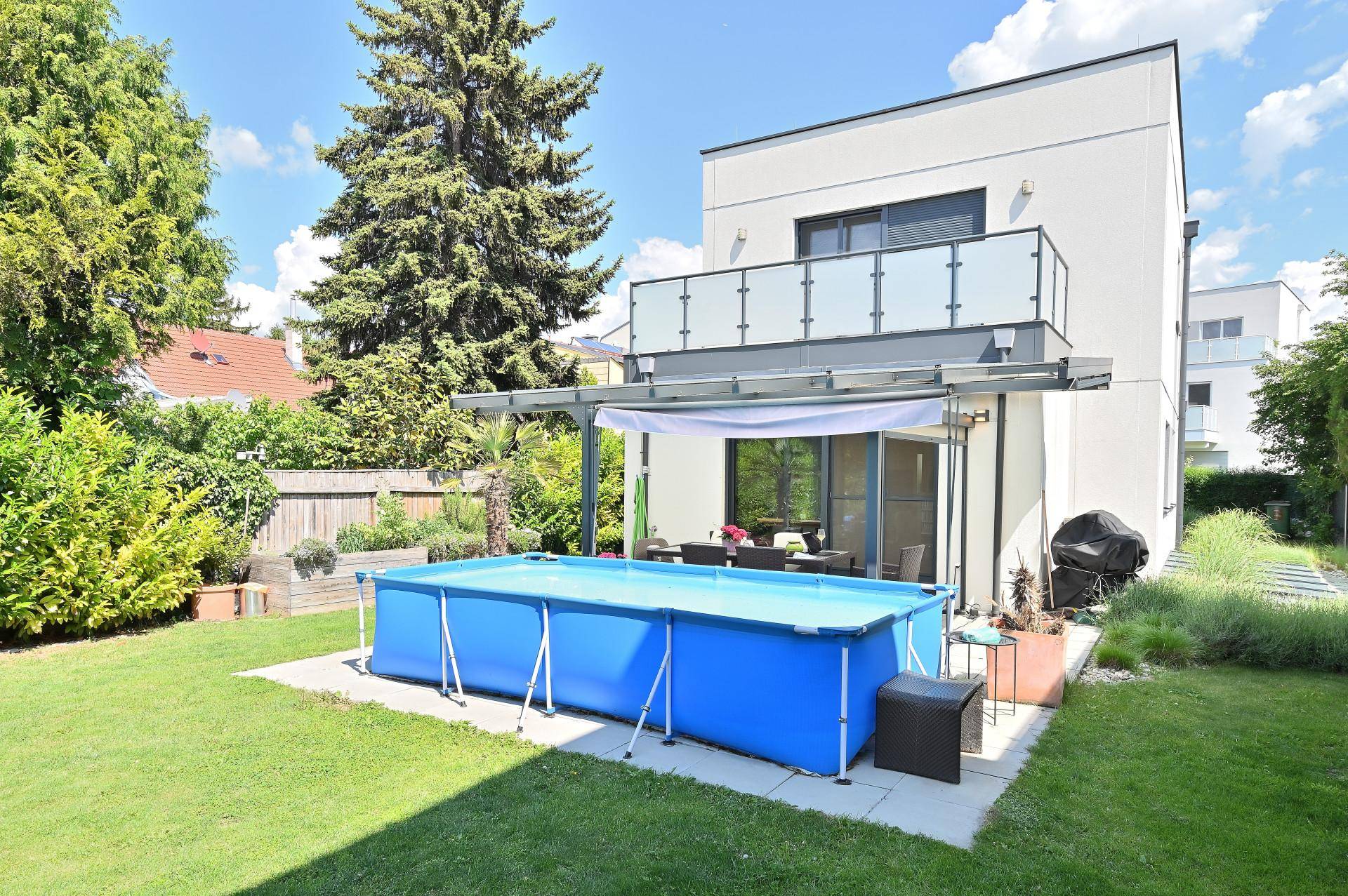 Hinterhof mit großem Aufstellpool, überdachter Terrasse und moderner Hausfassade.