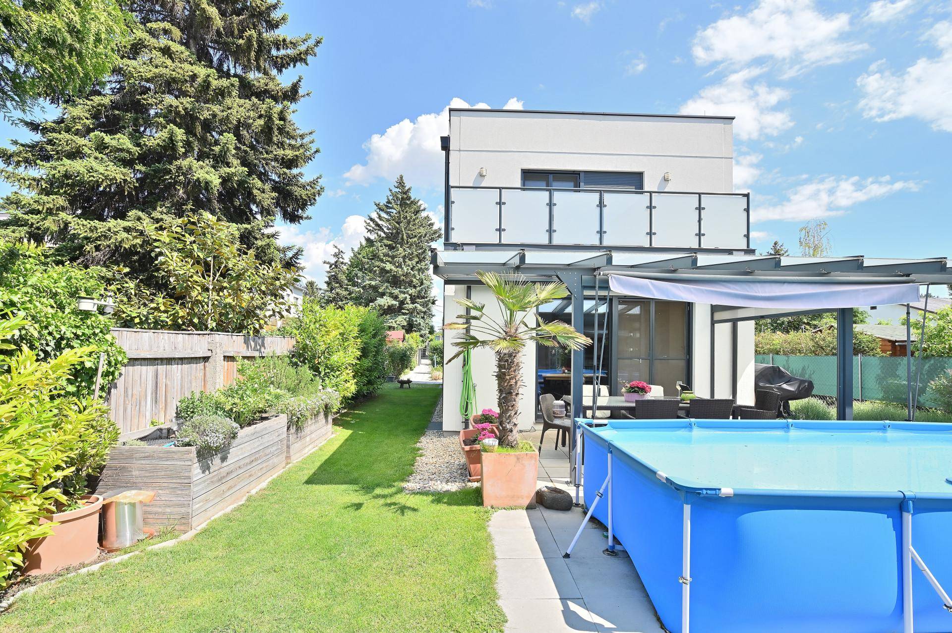 Gepflegter Garten mit Hochbeeten, Aufstellpool und überdachter Terrasse.