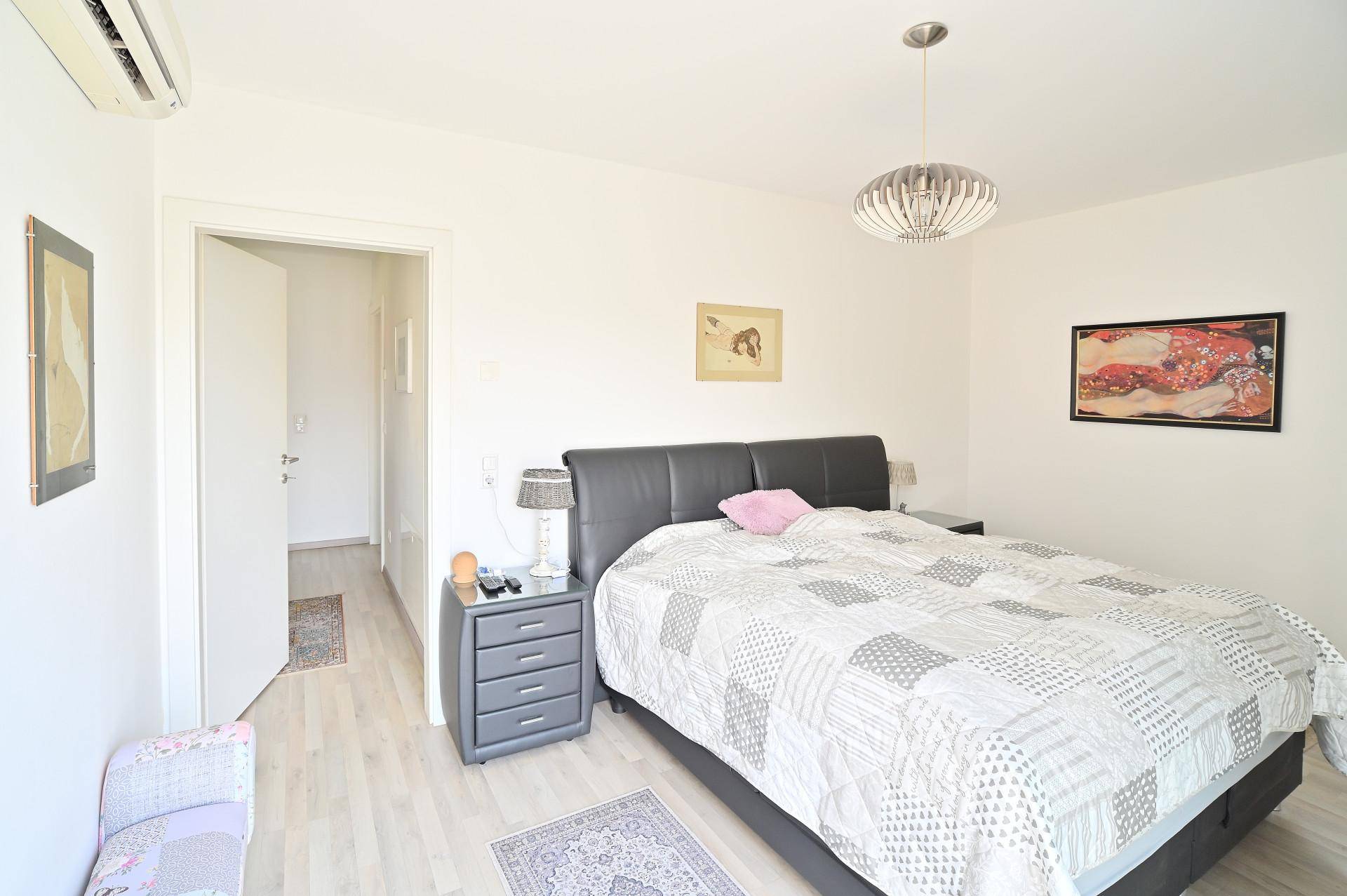 Helles Schlafzimmer mit Doppelbett, Nachttischen und Klimaanlage für angenehmes Raumklima.
