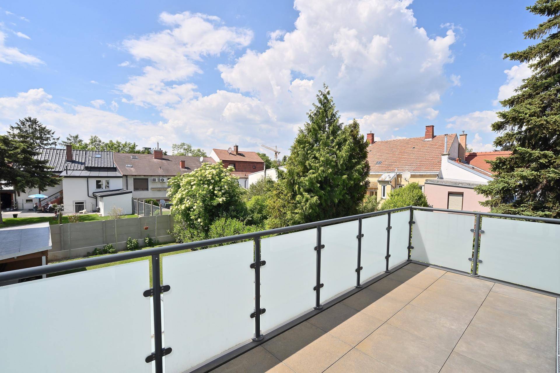 Geräumiger Balkon mit Glasgeländer und weitem Blick über die umliegende Nachbarschaft.
