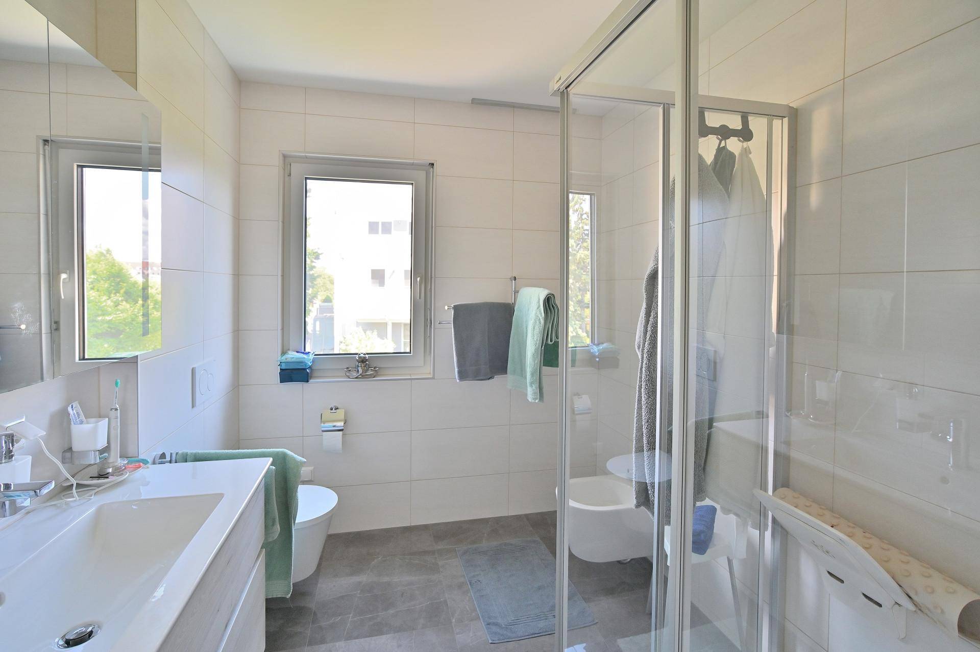Modernes Badezimmer mit Dusche, Doppelwaschbecken und Fenster für Tageslicht.