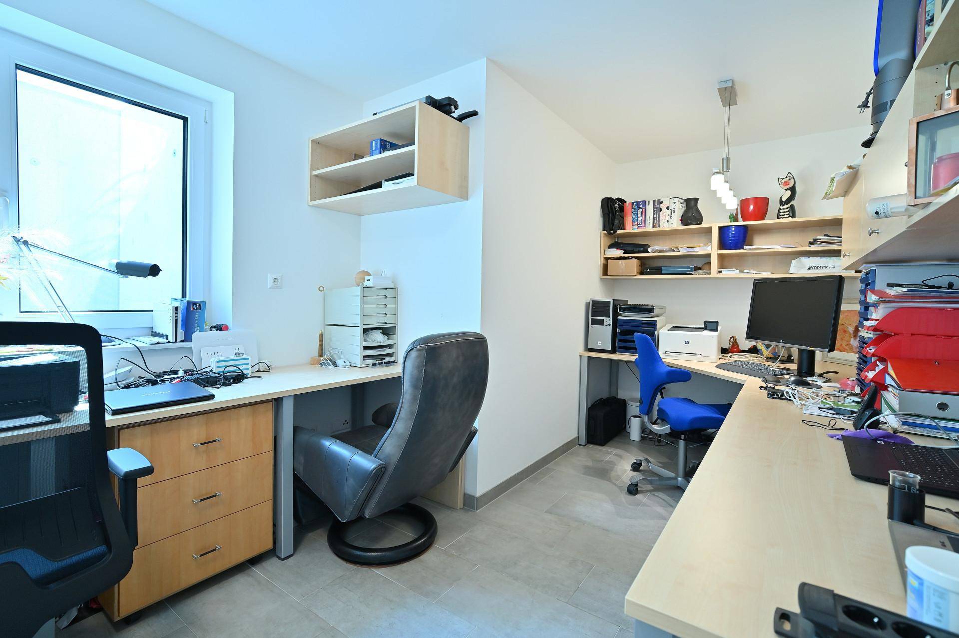 Funktionales Heimbüro mit zwei Arbeitsplätzen, Regalen und natürlichem Lichteinfall durch das große Fenster.