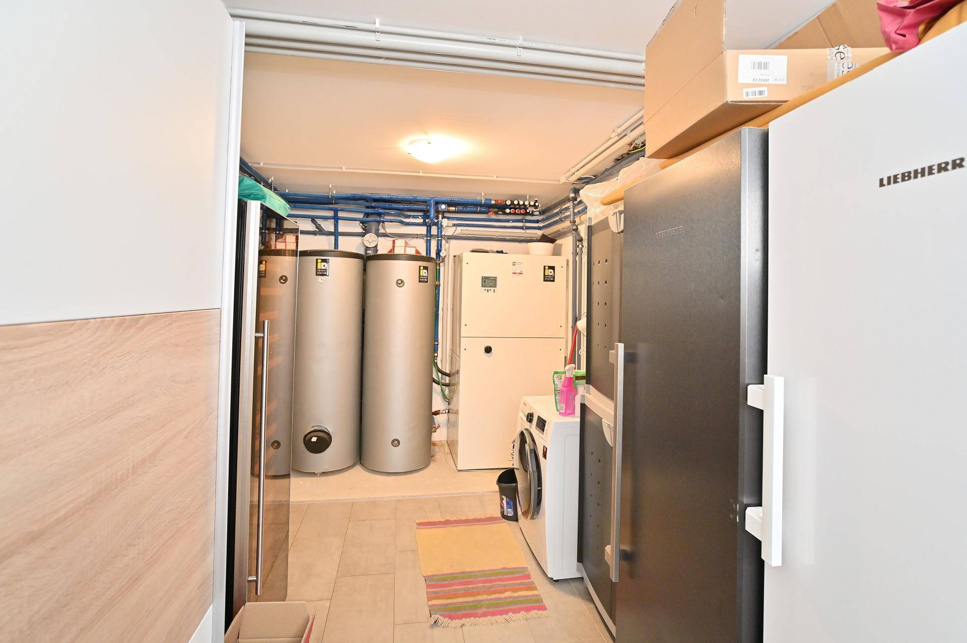 Technikraum im Keller mit Warmwasserspeichern, Waschmaschine und zusätzlichen Kühlgeräten für den Haushalt.
