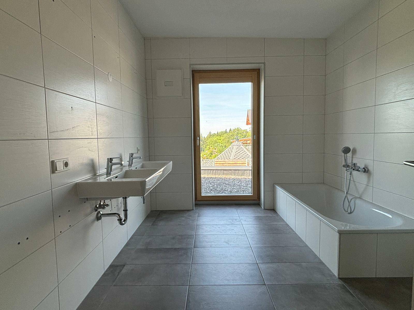 Modernes Badezimmer mit Doppelwaschbecken, Badewanne und Fenster für Tageslicht.