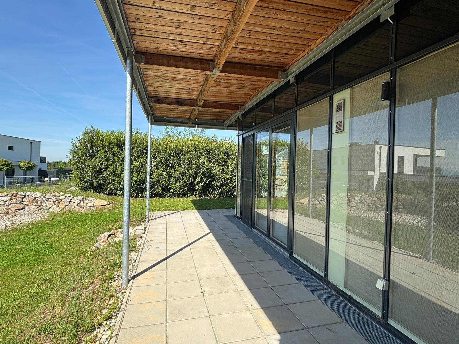 Überdachte Terrasse mit Holzdach und Zugang zum Garten, ideal für entspannte Stunden im Freien.