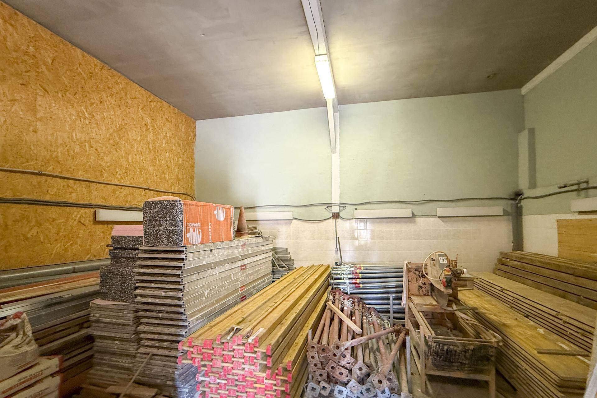 Lagerraum mit gestapelten Baumaterialien, Schalungen und Holzplatten, bereit für Bauarbeiten.