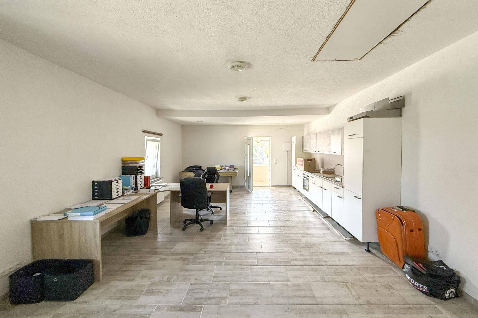 Großes Büro mit integrierter Küchenzeile, mehreren Arbeitsplätzen und viel Tageslicht.