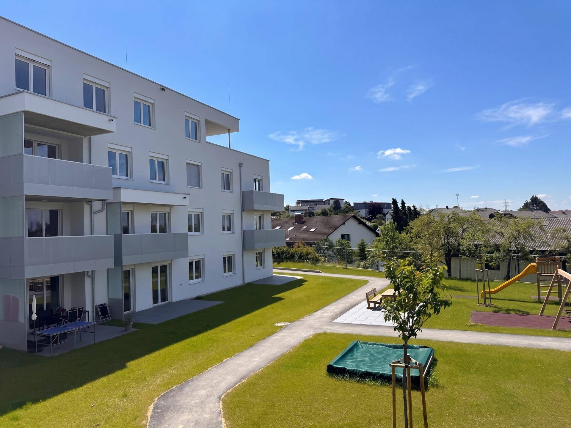 Neubau mit großzügiger Grünfläche und Kinderspielplatz im Außenbereich, perfekt für Familien.