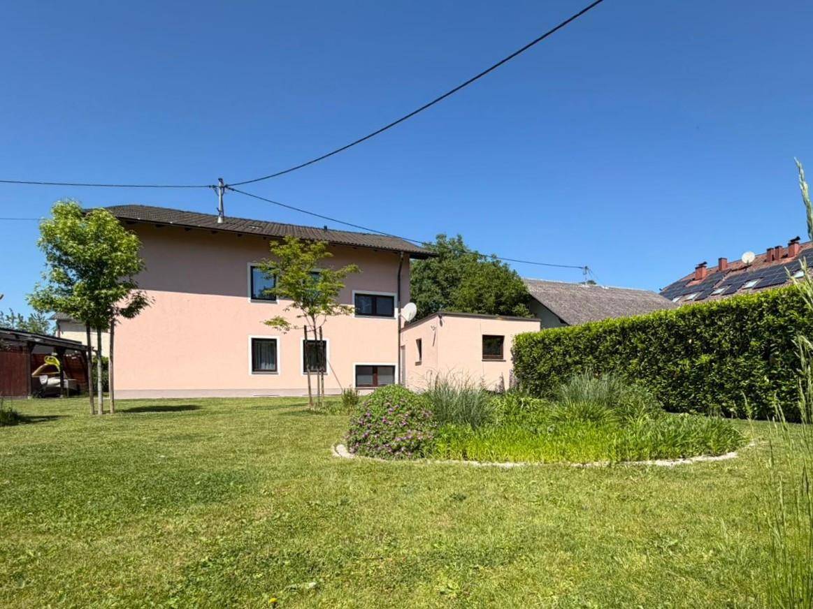 Rückansicht des Hauses mit großem, sonnigen Garten und gepflegten Grünflächen an einem klaren Tag.